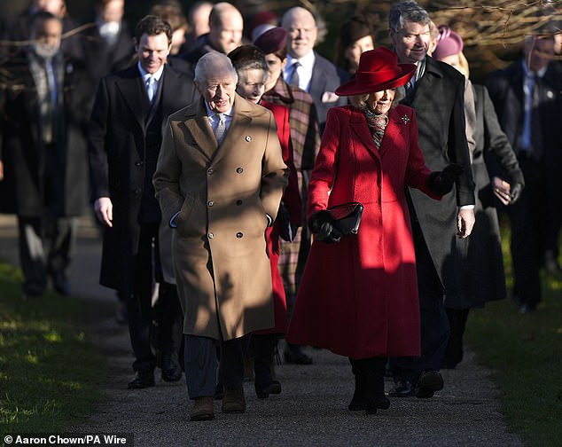 Queen Camilla in a festive red coat walking alongside King Charles at Sandringham