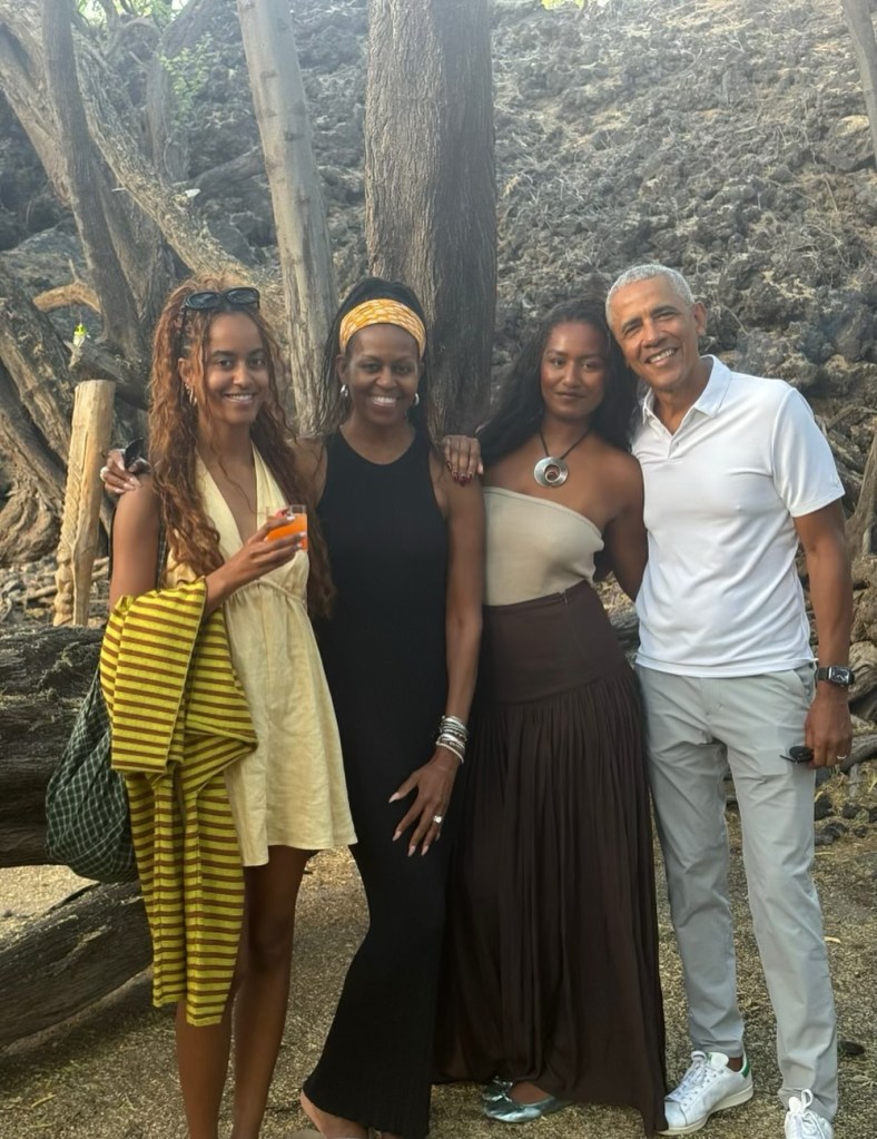 Malia, Michelle, Sasha, and Barack Obama smiling together.