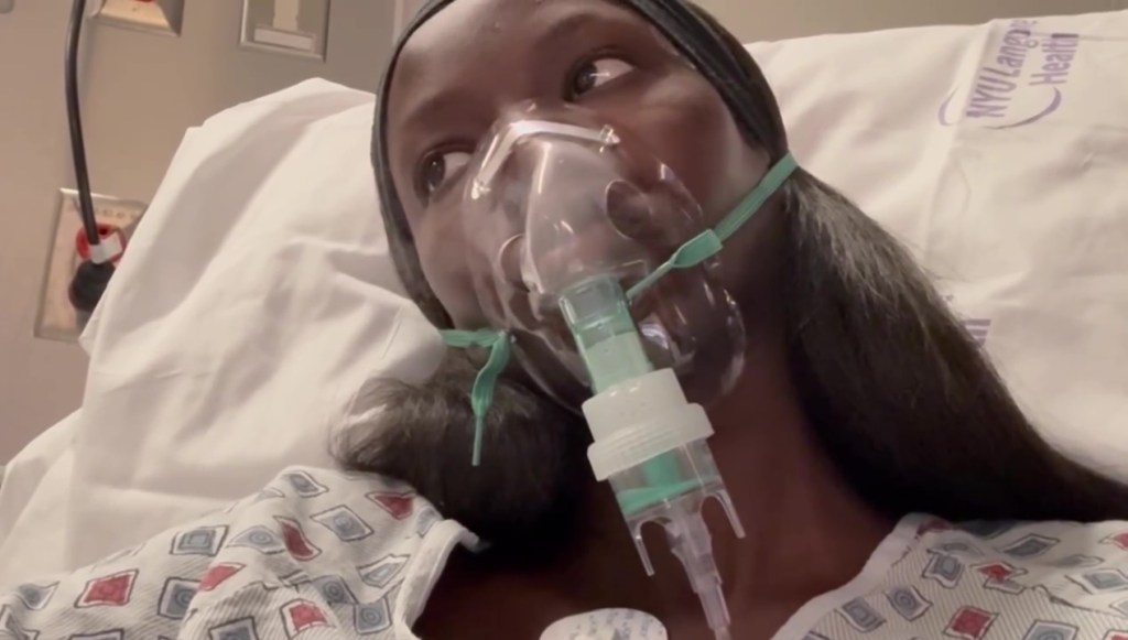 Anok Yai in a hospital bed wearing an oxygen mask after revealing her congenital lung defect.