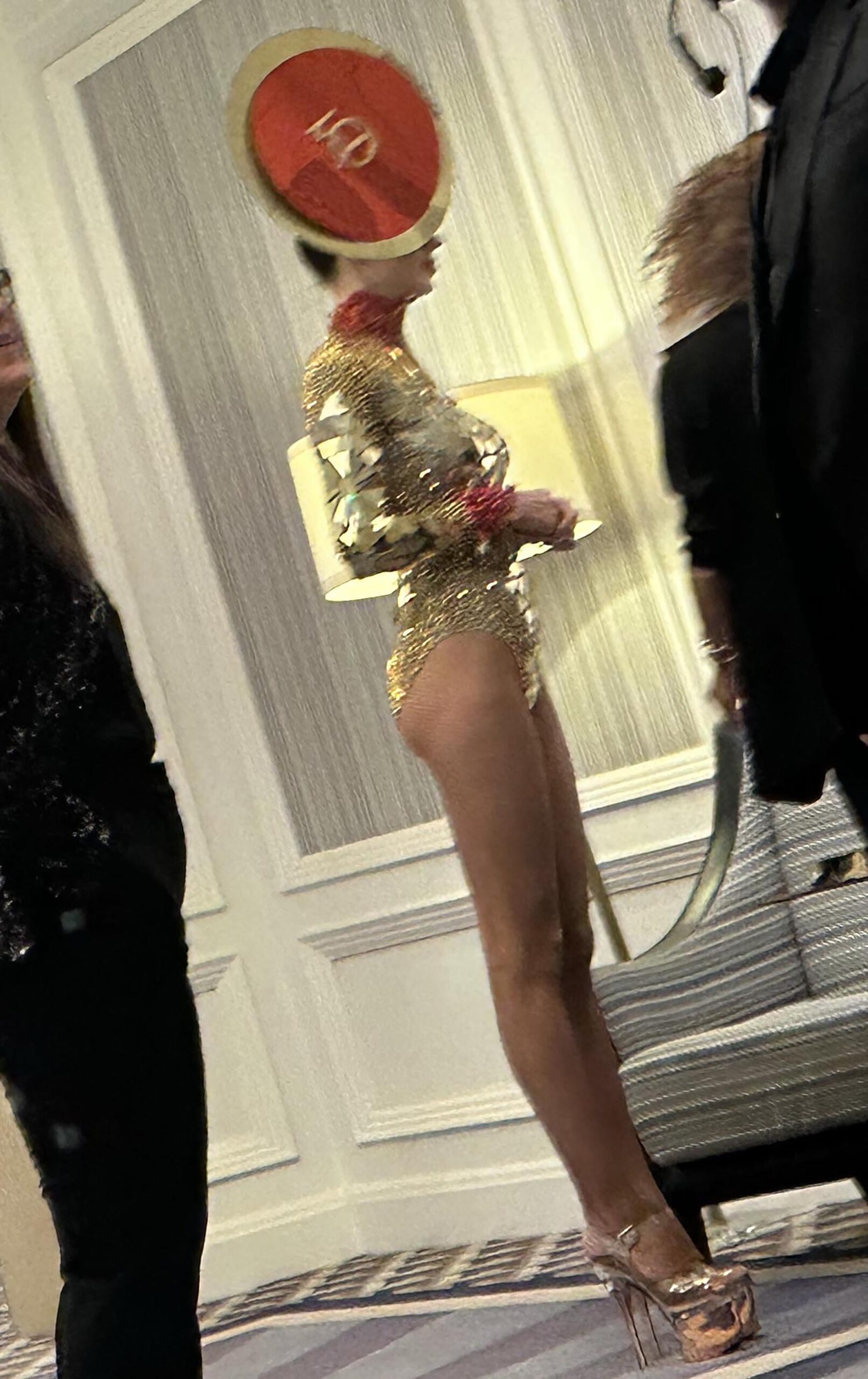 An entertainer in a gold bodysuit and red '50' hat at Tiger Woods' birthday event.