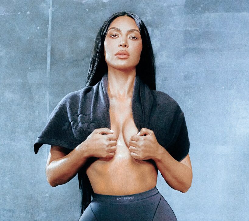 Kim Kardashian West, with long dark hair, wearing a gray shirt wrapped around her chest, and gray pants, posing for Complex Magazine.