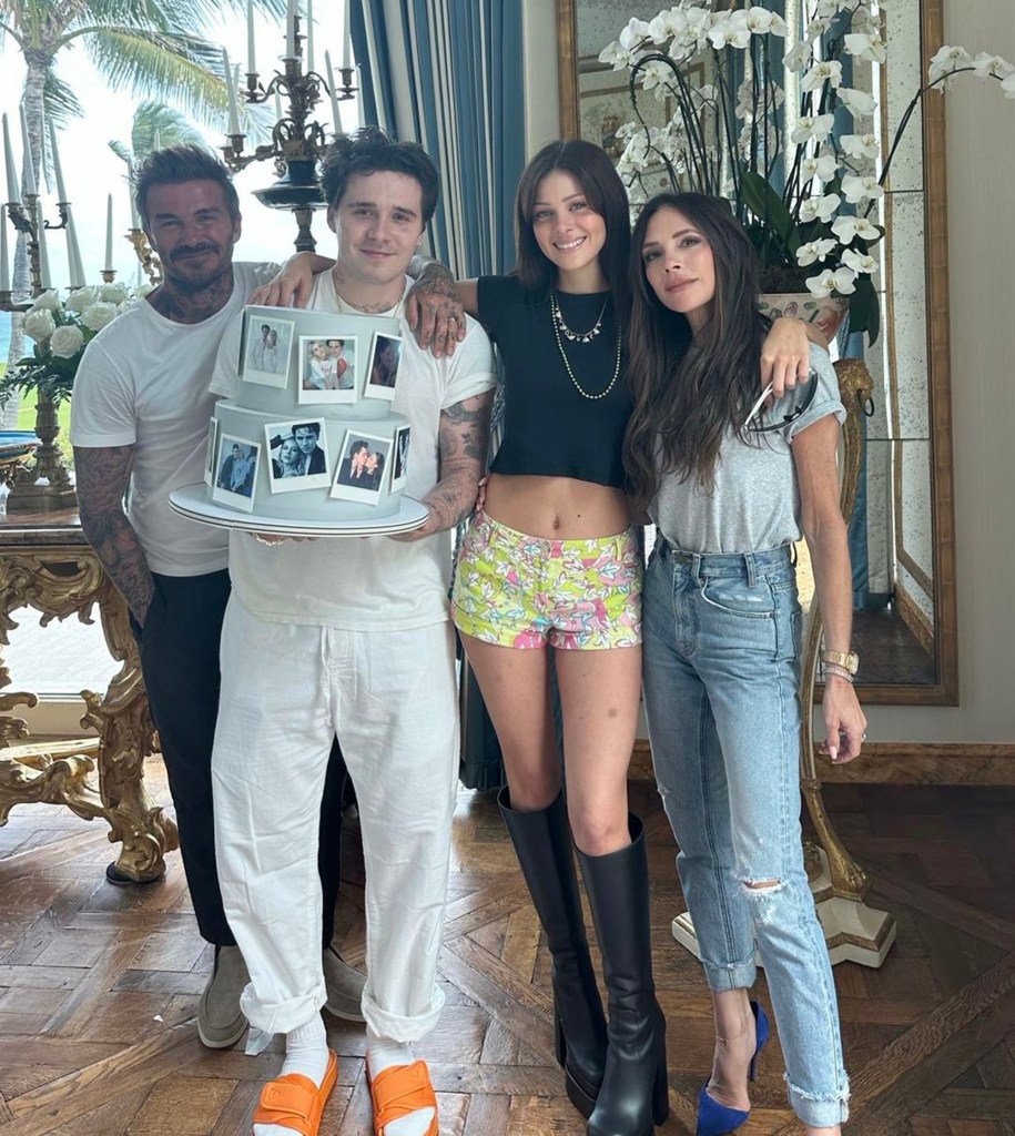 David and Victoria Beckham with their children posing around a cake.