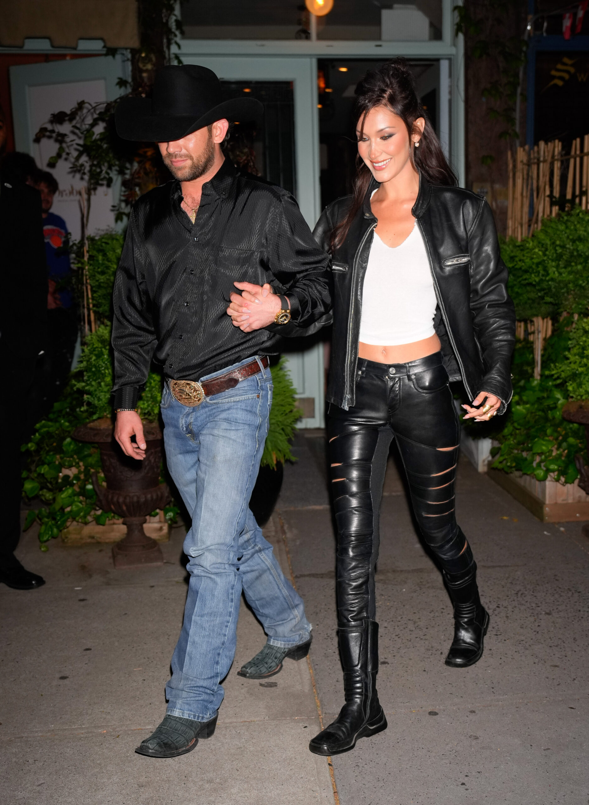 Bella Hadid and Adan Banuelos walking outdoors at night.