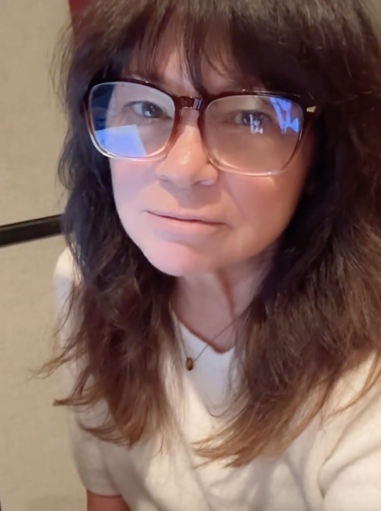 Valerie Bertinelli wearing glasses and a white top, looking directly at the camera.