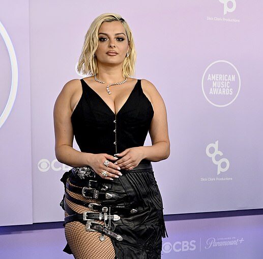 Bebe Rexha wearing a black bodysuit with a textured leather skirt, fishnets, and hardware on the 2026 AMAs red carpet.