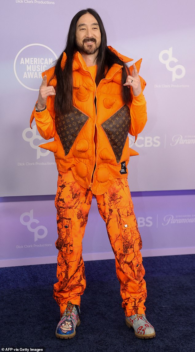 Steve Aoki in a bright orange spiky jacket with matching cargo pants and mismatched shoes at the 2026 AMAs.