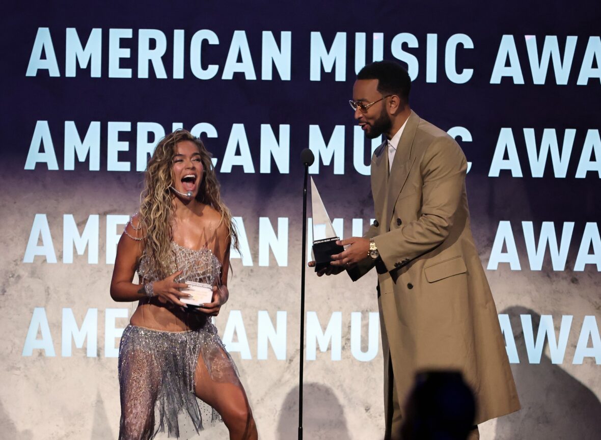 Karol G reacts onstage during a surprise trophy presentation at the AMAs.