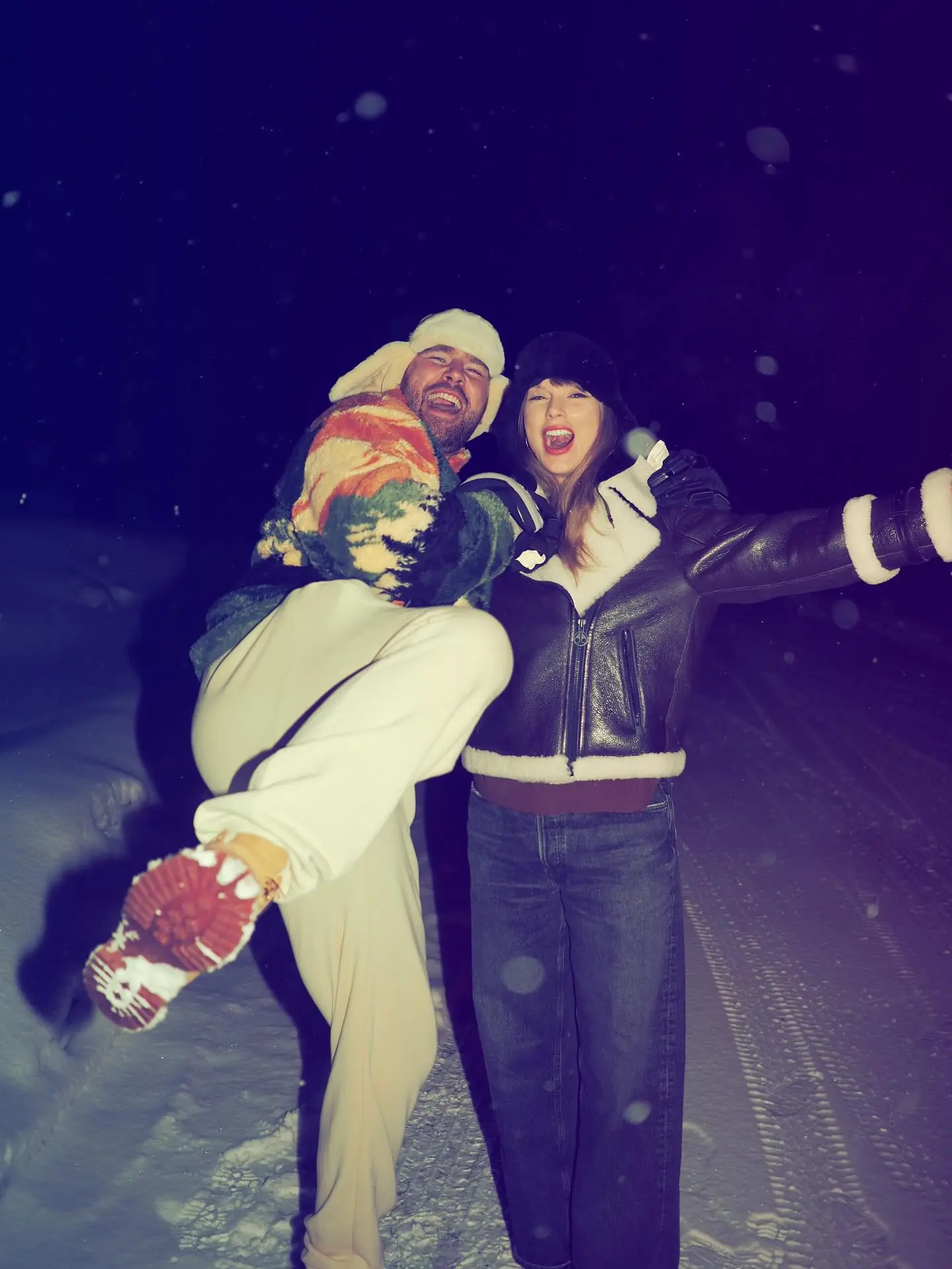 Taylor Swift and Travis Kelce pose together in the snow at night.