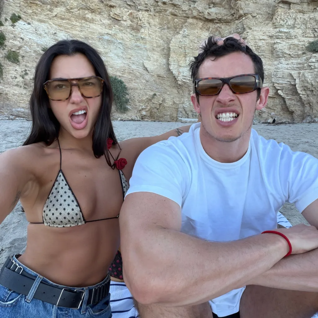 Dua Lipa and Callum Turner on a beach, making funny faces (March 2026).