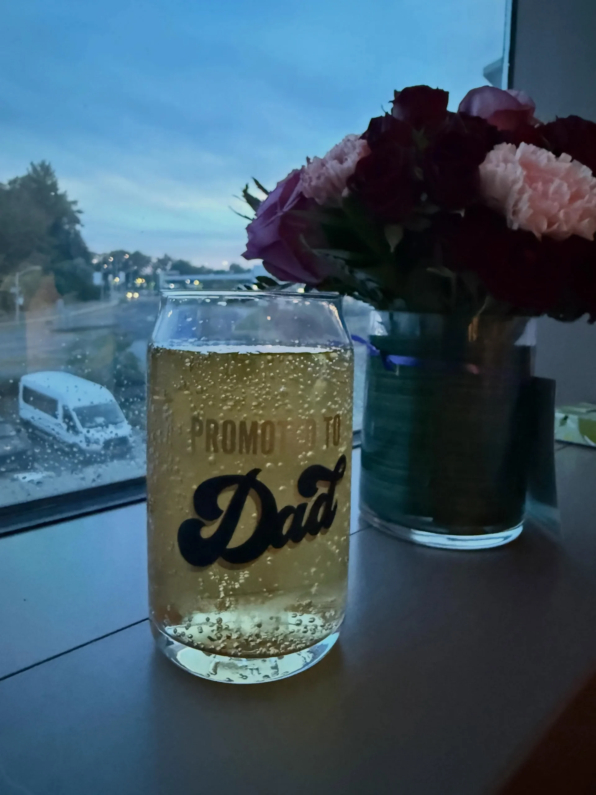 A glass reading "Promoted to Dad" beside flowers, celebrating first Father's Day after Aidan's early arrival.